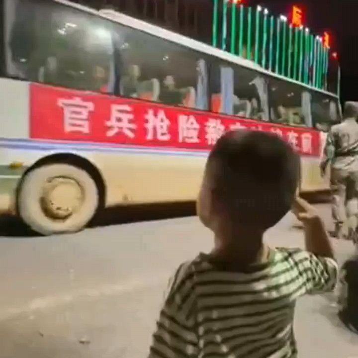 小男孩向抗洪抢险救灾车队敬礼